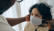 An adult puts a mask on a child