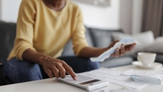 Person using calculator and holding piece of paper