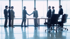 Group of businesspeople meeting with two shaking hands