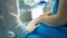 Doctor puts gloved hand on patient hand during examination  
