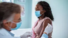 woman receives a shot from a male clinician