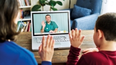 A parent and child wave to a provider via video chat