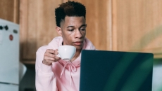 A person using a computer and holding a teacup