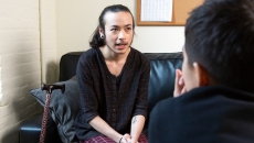 A person with a cane speaking to a healthcare provider
