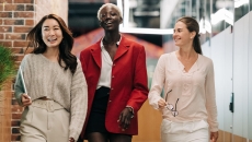 Three people walk toward the camera in an office setting.