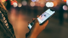 A person holding a phone by a street.