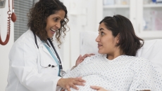 A pregnant patient talking with a doctor in a hospital.