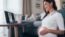 A pregnant person looking at a doctor onscreen