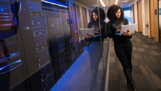 A security professional leans on a window to a server room