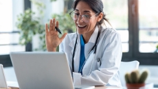 Doctor waving at laptop screen