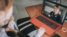 A patient with a baby on their lap speaks to a provider via telehealth