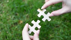 Hands fit two puzzle pieces together
