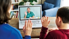 Two patients waving to a clinician on a screen