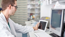 A clinician using both desktop computer and tablet