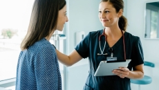 A nurse holding a tablet while speaking with a patient