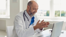 A doctor uses a laptop for an online consultation