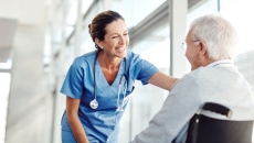 A nurse talking to an elderly patient in a wheelchair