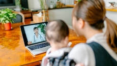 A mother with her baby is in an online consultation with a doctor