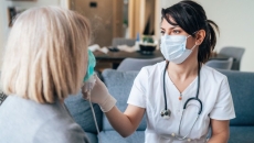 A nurse applying medical inhalation treatment through the mask of a senior patient