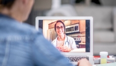 A doctor having a virtual consultation with a patient using a laptop
