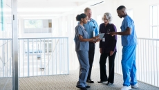 Nurses and doctors gather in a hallway for a discussion