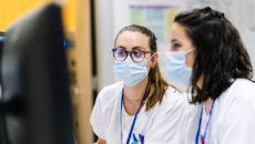 Two hospital staff wearing masks looking at a desktop computer