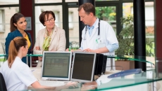 Hospital staff in a discussion around the nurses station