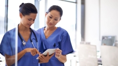 Two nurses reviewing a medical record from a digital tablet