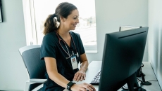A doctor reading a patient's medical record on a desktop computer