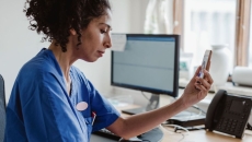 Doctor using a smartphone sitting at a computer desk