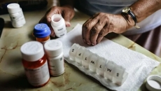Hands are putting medications in a daily prescription sorting box