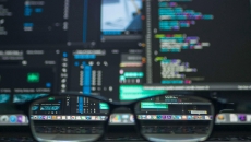 Glasses in front of computer screens with software code 
