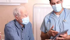 A doctor reviews information with a senior man in outpatient care 
