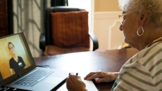 An elderly patient in a virtual consult with a doctor using a laptop computer