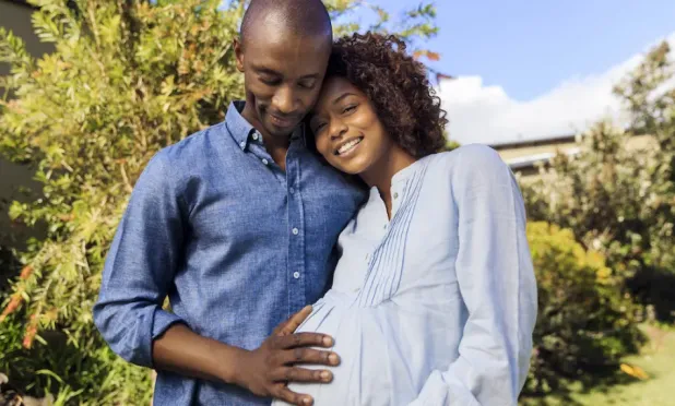 Person with hand on pregnant person's belly