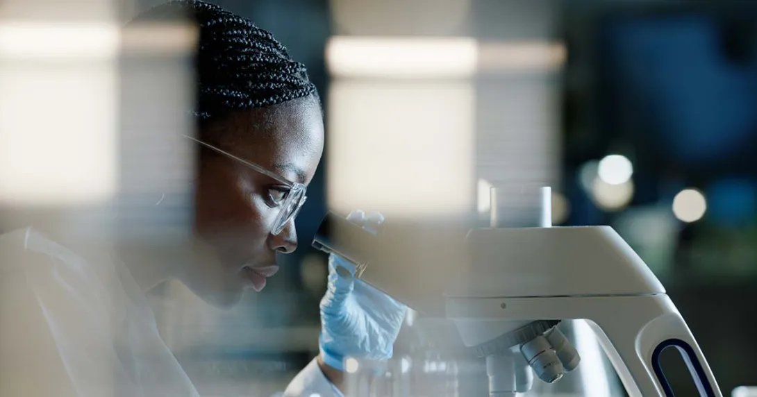 physician looking through microscope for precision medicine