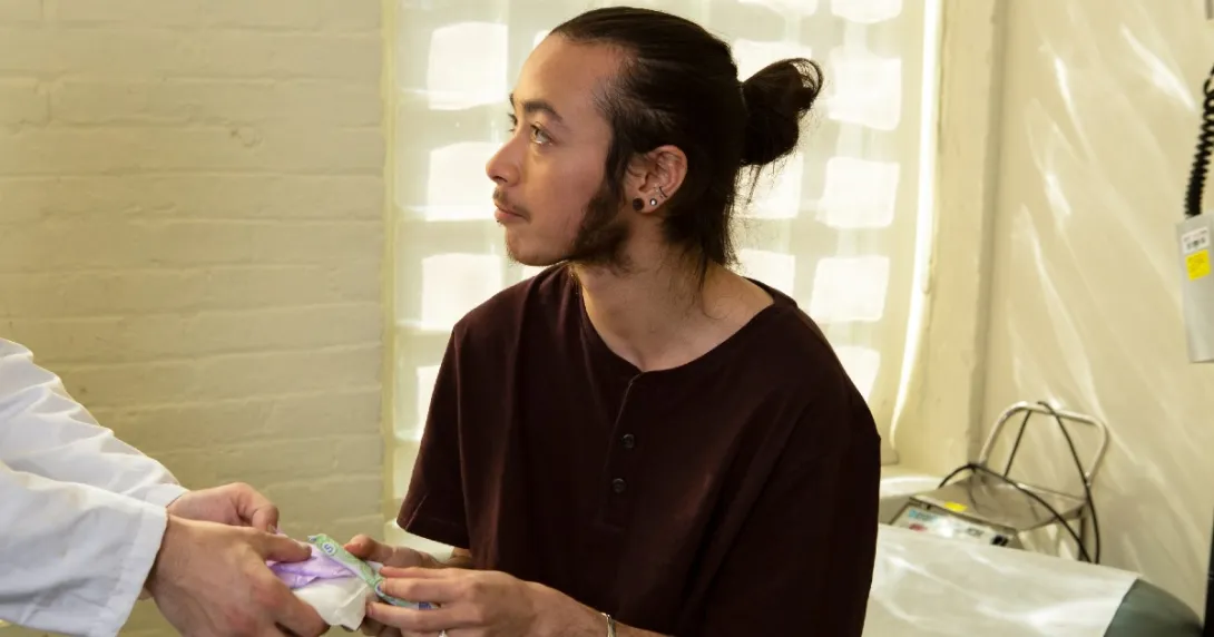 A genderqueer person receiving menstrual products from a doctor