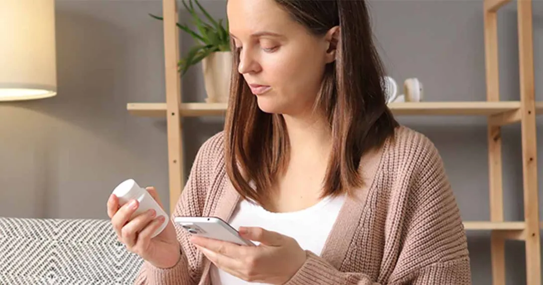 Person holding pill bottle and smart phone Person holding pill bottle and smart phone