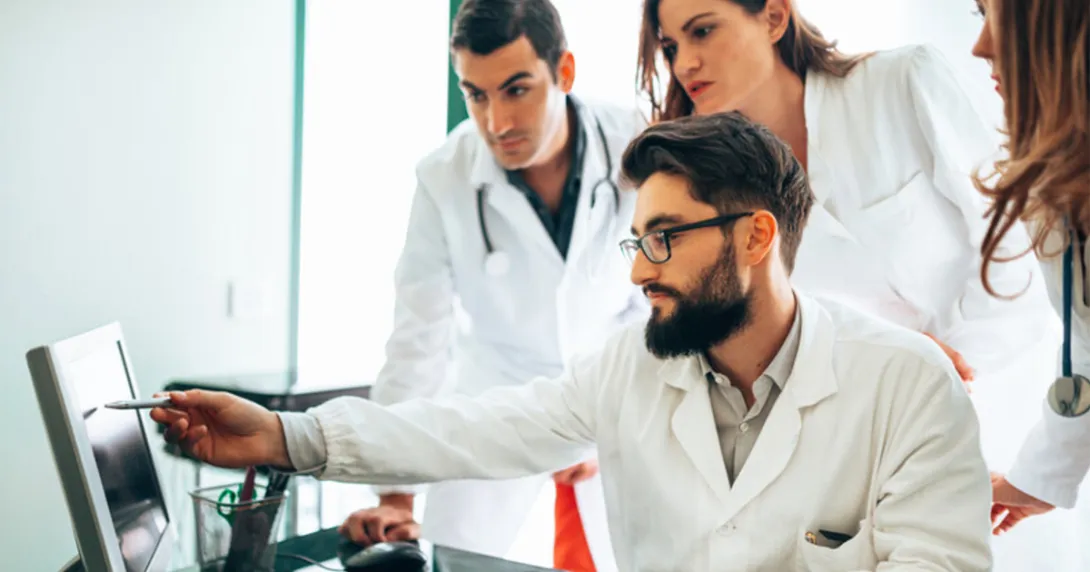 People in medical wear at a screen