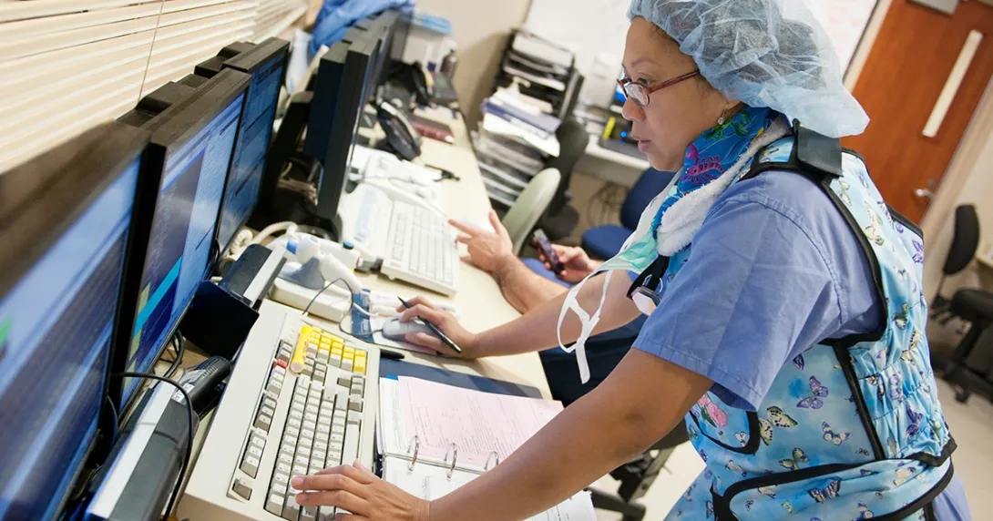 person in PPE at computer, health IT