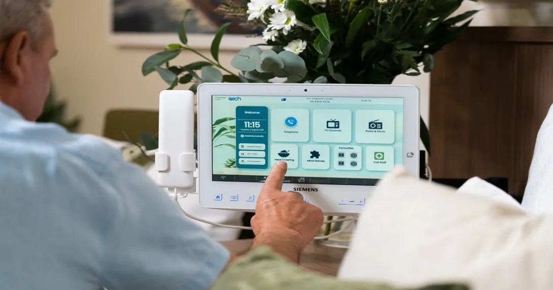 A senior patient using a bedside tablet to order a meal.
