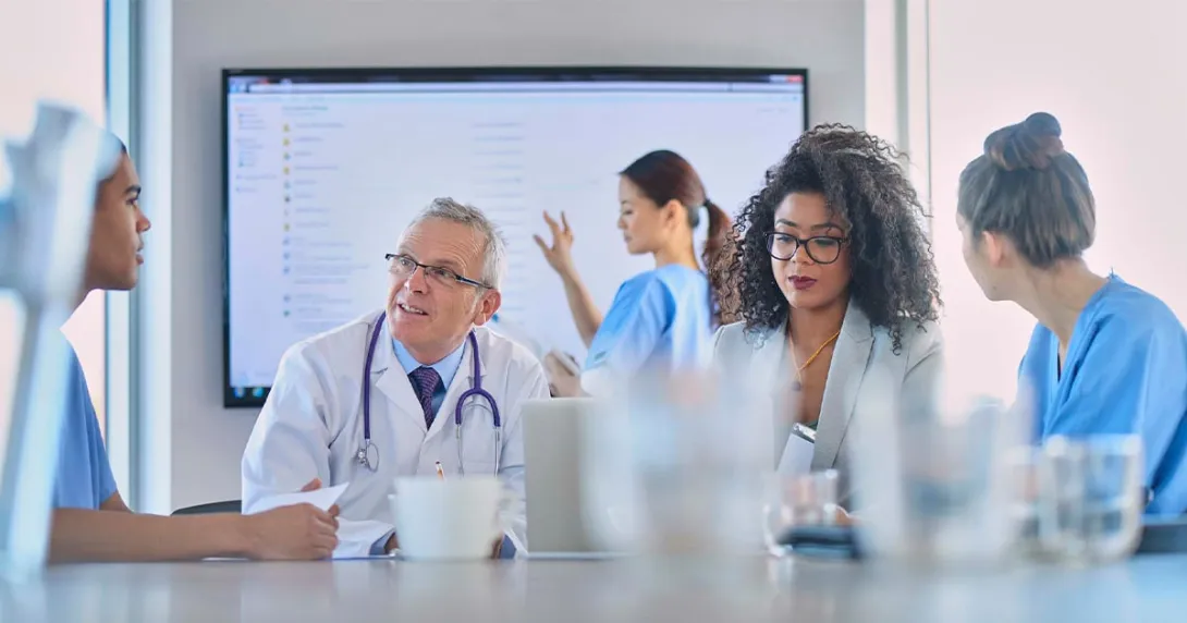 Healthcare workers meeting with large screen in background Healthcare workers meeting with large screen in background