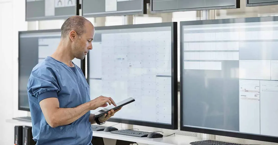 Healthcare worker with tablet looking at data displays Healthcare worker with tablet looking at data displays
