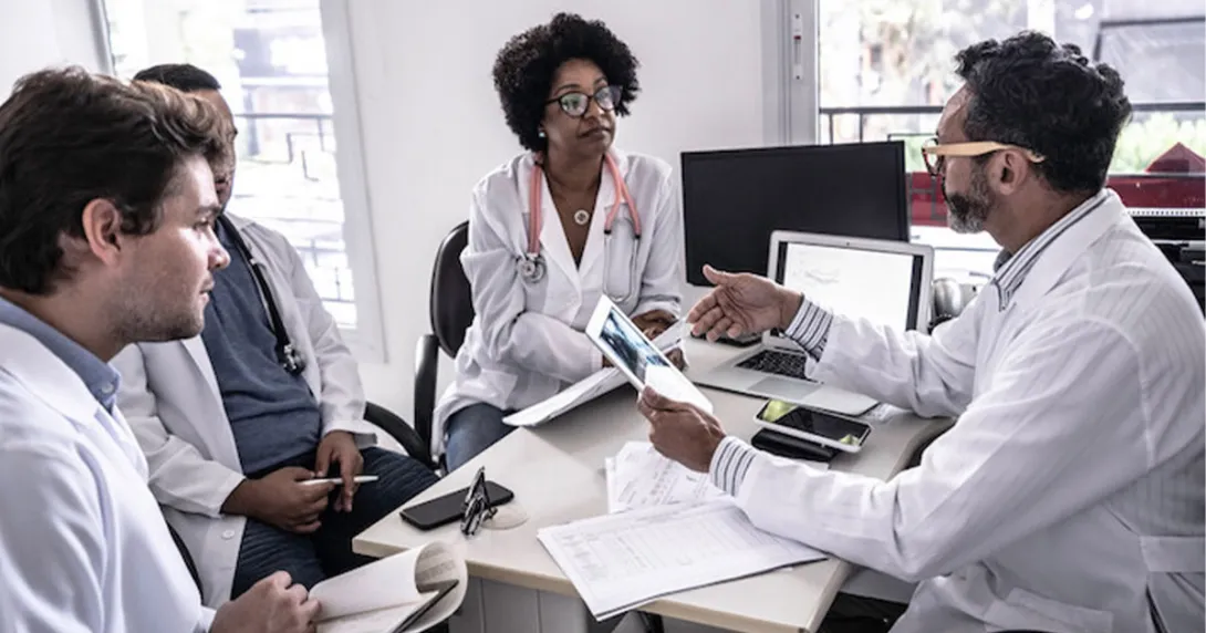 Doctors sitting at a desk and discussing data Doctors sitting at a desk and discussing data