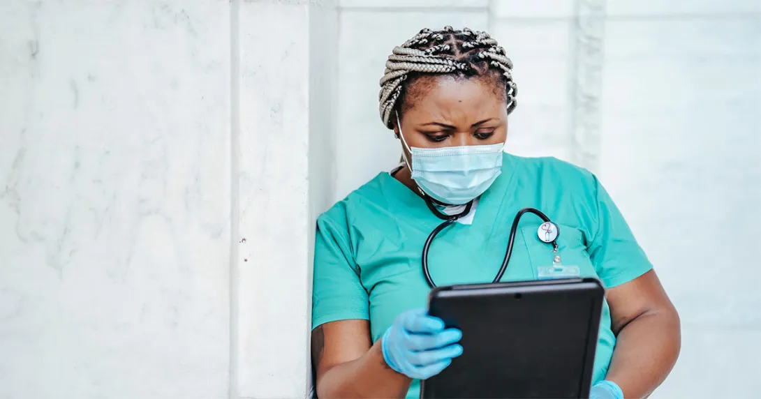Healthcare worker in mask looking at tablet