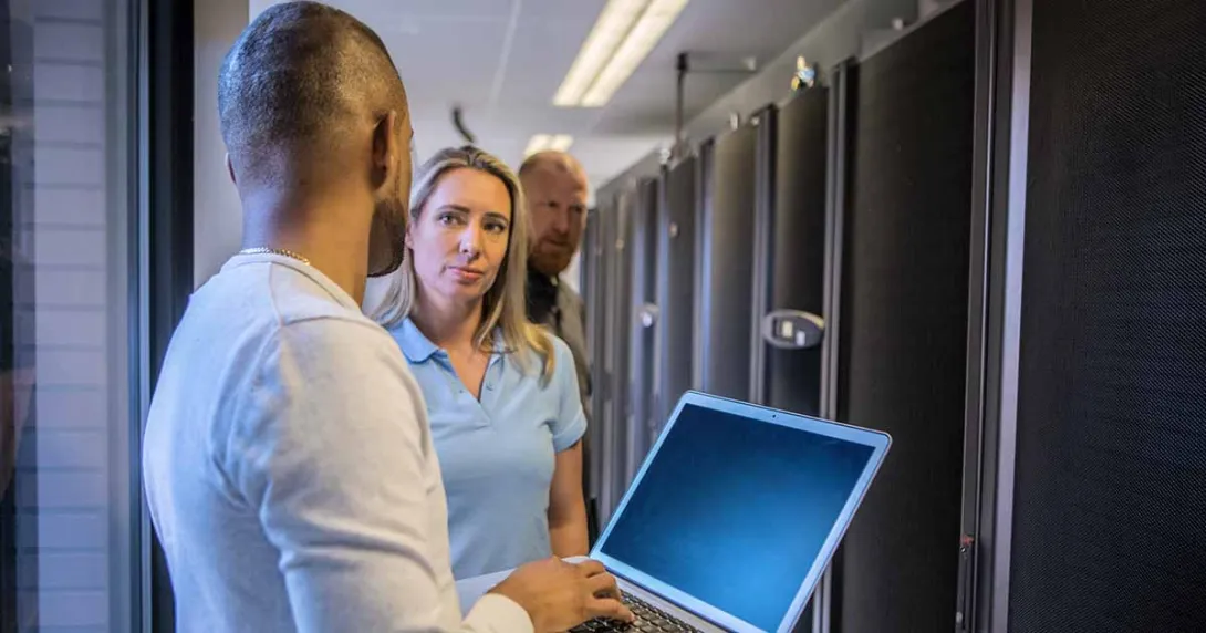 Worker with laptop talking to other IT workers Worker with laptop talking to other IT workers