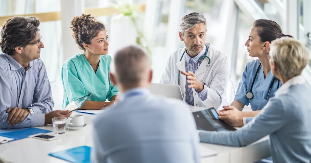 Doctors and payers sit around a table. Doctors and payers sit around a table discussing claims data, prior authorizations and more.