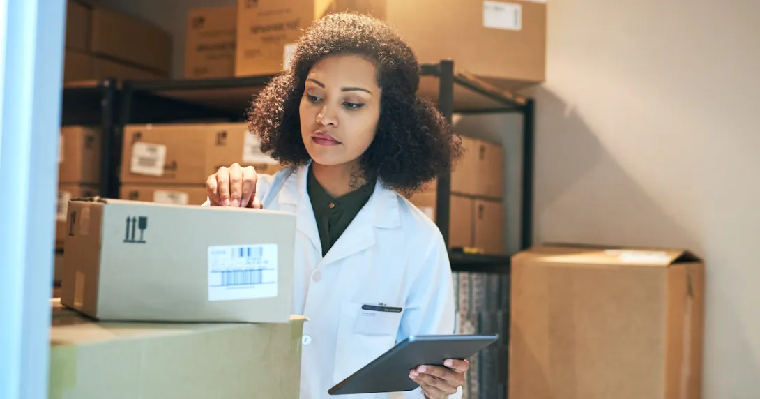 A pharmacist using a digital tablet while doing inventory in the pharmacy stockroom A pharmacist using a digital tablet while doing inventory in the pharmacy stockroom