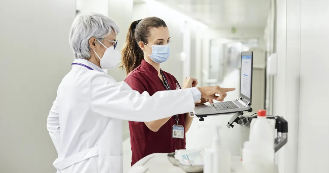 A doctor and nurse using a laptop along the hospital corridor