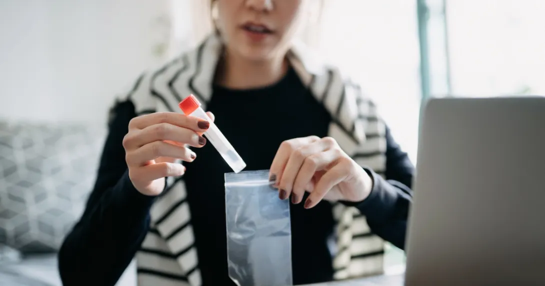 A person placing a medical test tube inside a plastic bag A person placing a medical test tube inside a plastic bag
